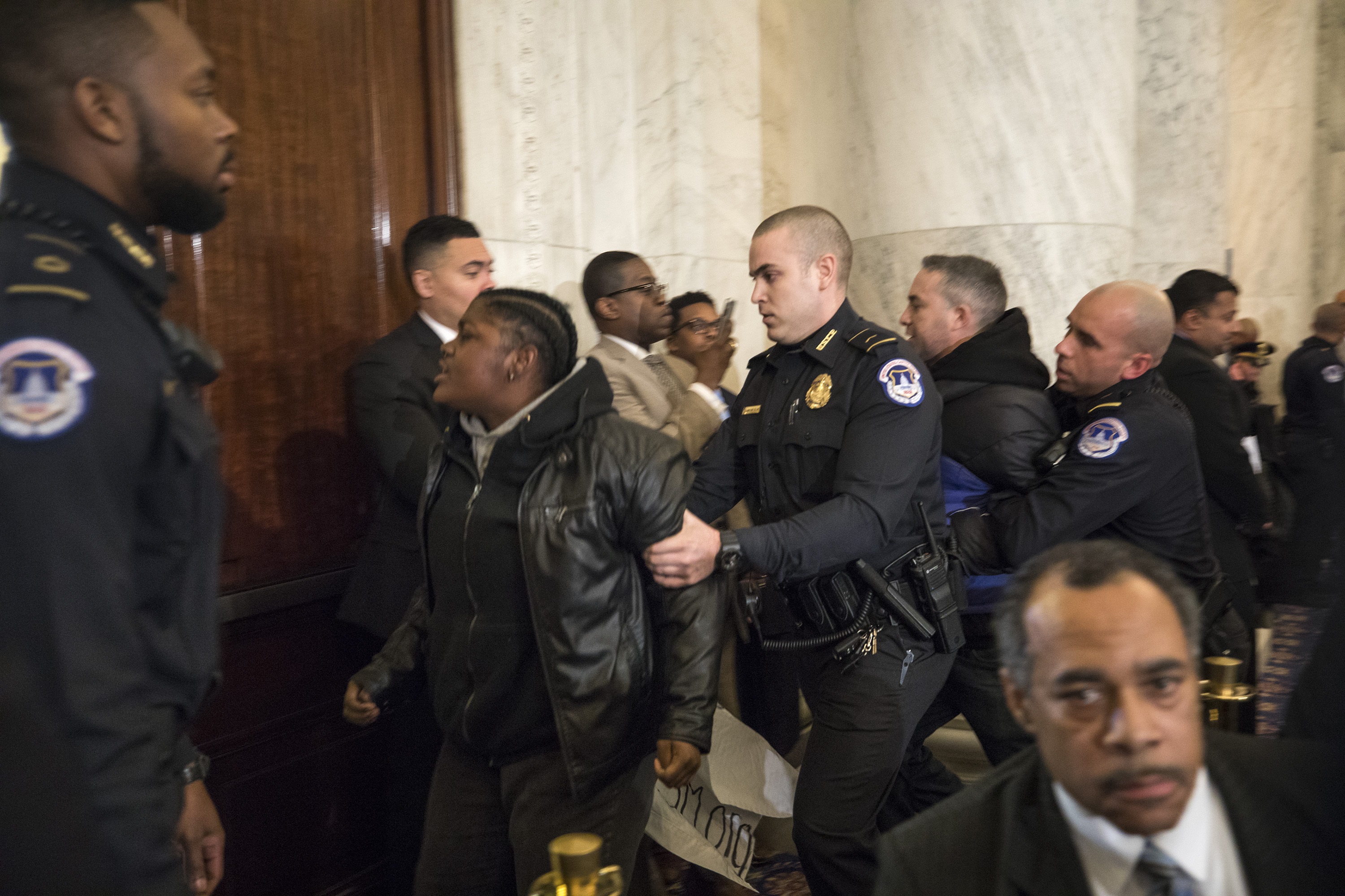Protesters being removed from the hearing. (Photo courtesy of Jim Lo Scalzo/ European Pressphoto Agency)