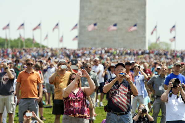 Spectators watch World War II era aircraft as they fly over the World War II Memorial. (Tom Williams/CQ Roll Call)