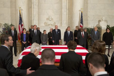 The family of late Supreme Court Justice Antonin Scalia take their seats as Supreme Court Justices stand for a private ceremony in the Great Hall of the Supreme Court in Washington, Friday, Feb. 19, 2016, where Scalia will lie in repose. From back left are Counselor to the Chief Justice Jeffrey Minear, and Supreme Court Justices Elena Kagan, Samuel Anthony Alito, Jr., Ruth Bader Ginsburg, Anthony M. Kennedy, Chief Justice John G. Roberts, Jr., Clarence Thomas, Stephen G. Breyer, and Sonia Sotomayor. (AP Photo/Jacquelyn Martin, Pool)